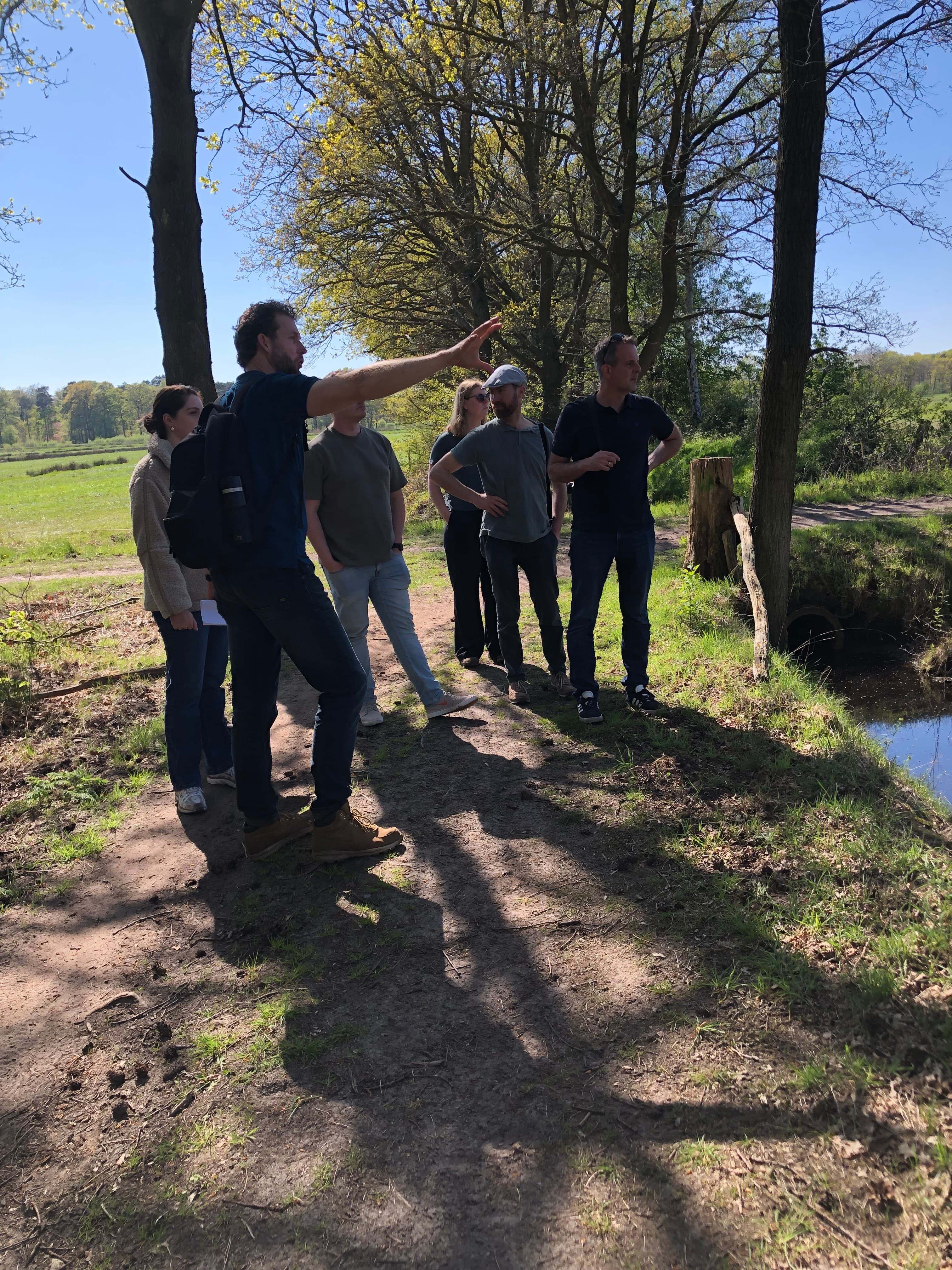 Jos wijst de groep langs een pad op het landschap aan de overkant.